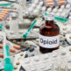 Opioid bottle surrounded by pills and syringes